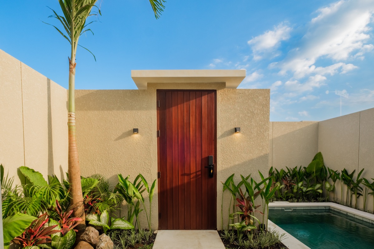 Tall timber door in a walled tropical garden beside a plunge pool at a Lario villa