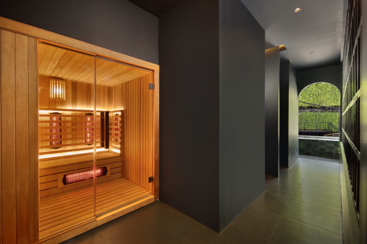 Glass-fronted red light infrared sauna cabin with timber benches at Found Wellness