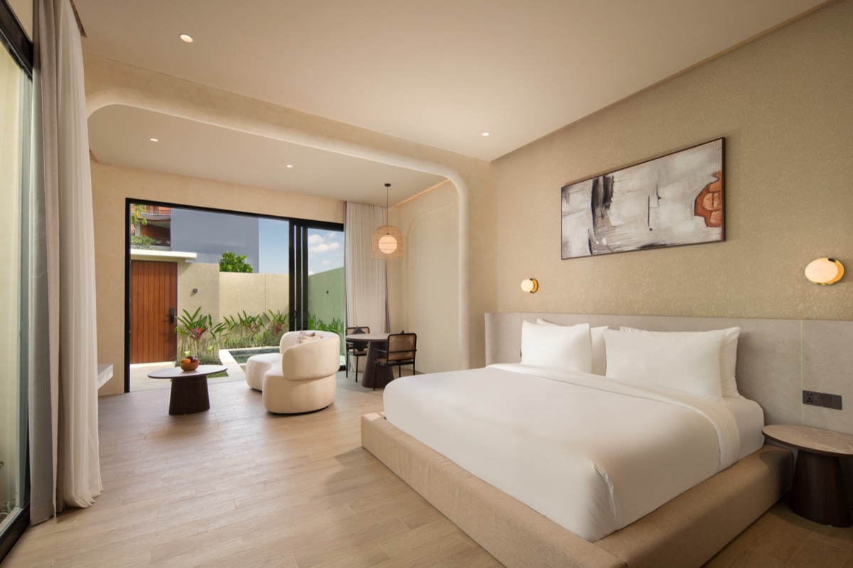 Lario Collection suite with a king bed, abstract artwork and open doors to a garden patio