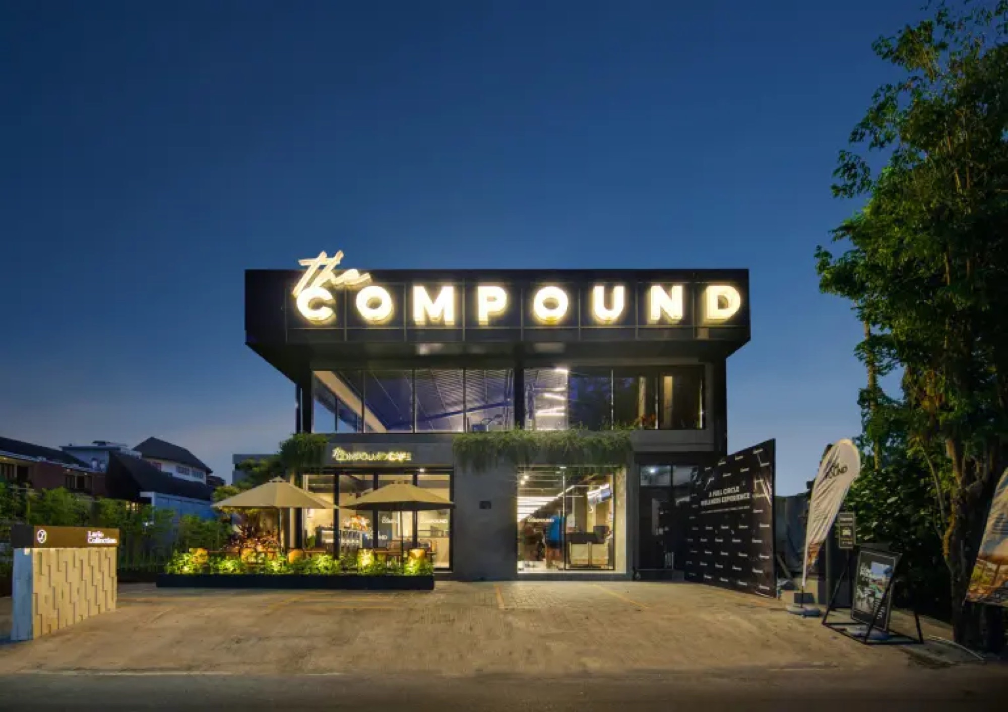The Compound Seminyak's illuminated two-storey building and café terrace at night