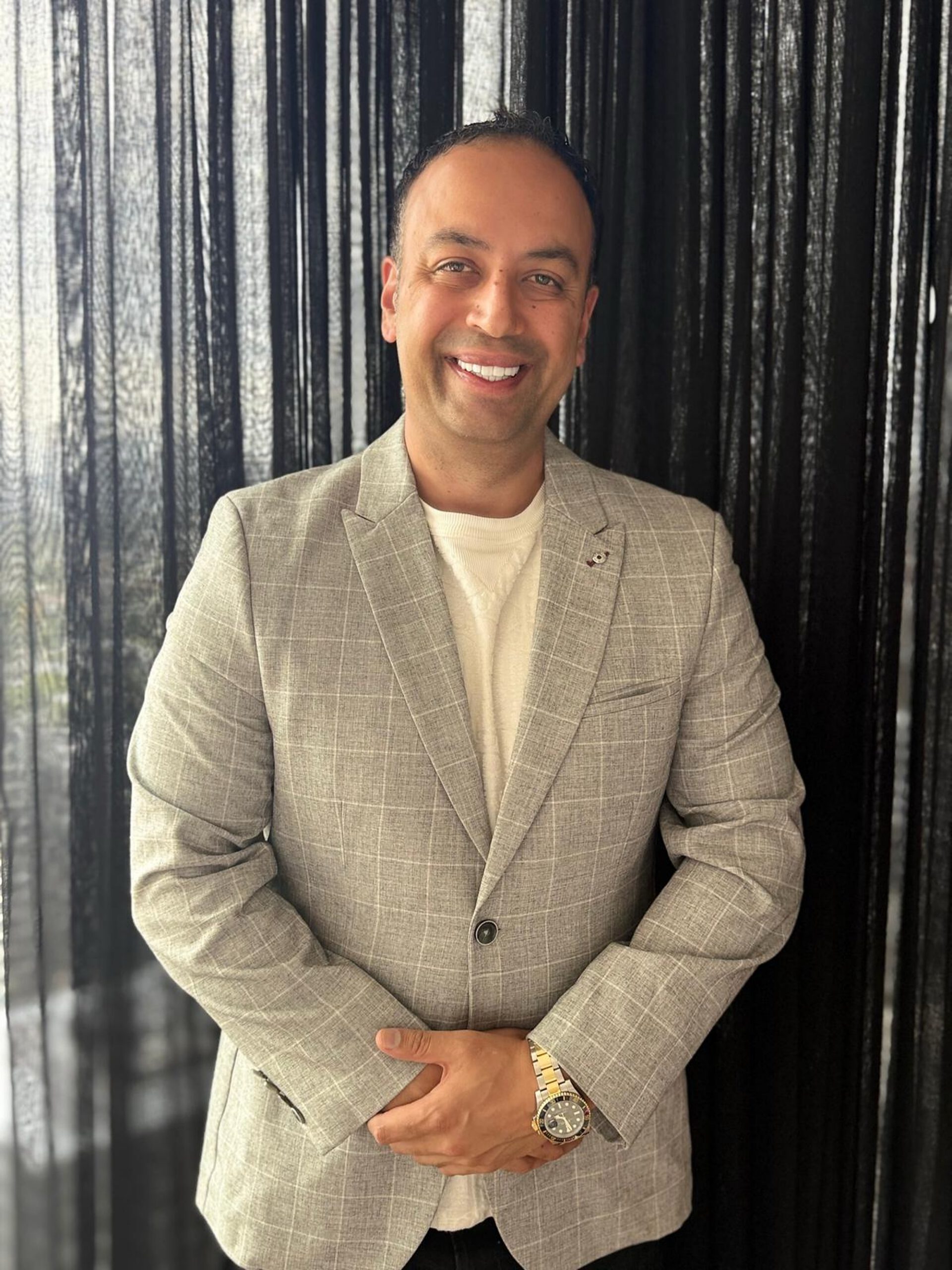 Jay Daha, Founder and CEO of JSD Collective, smiling in a light check blazer