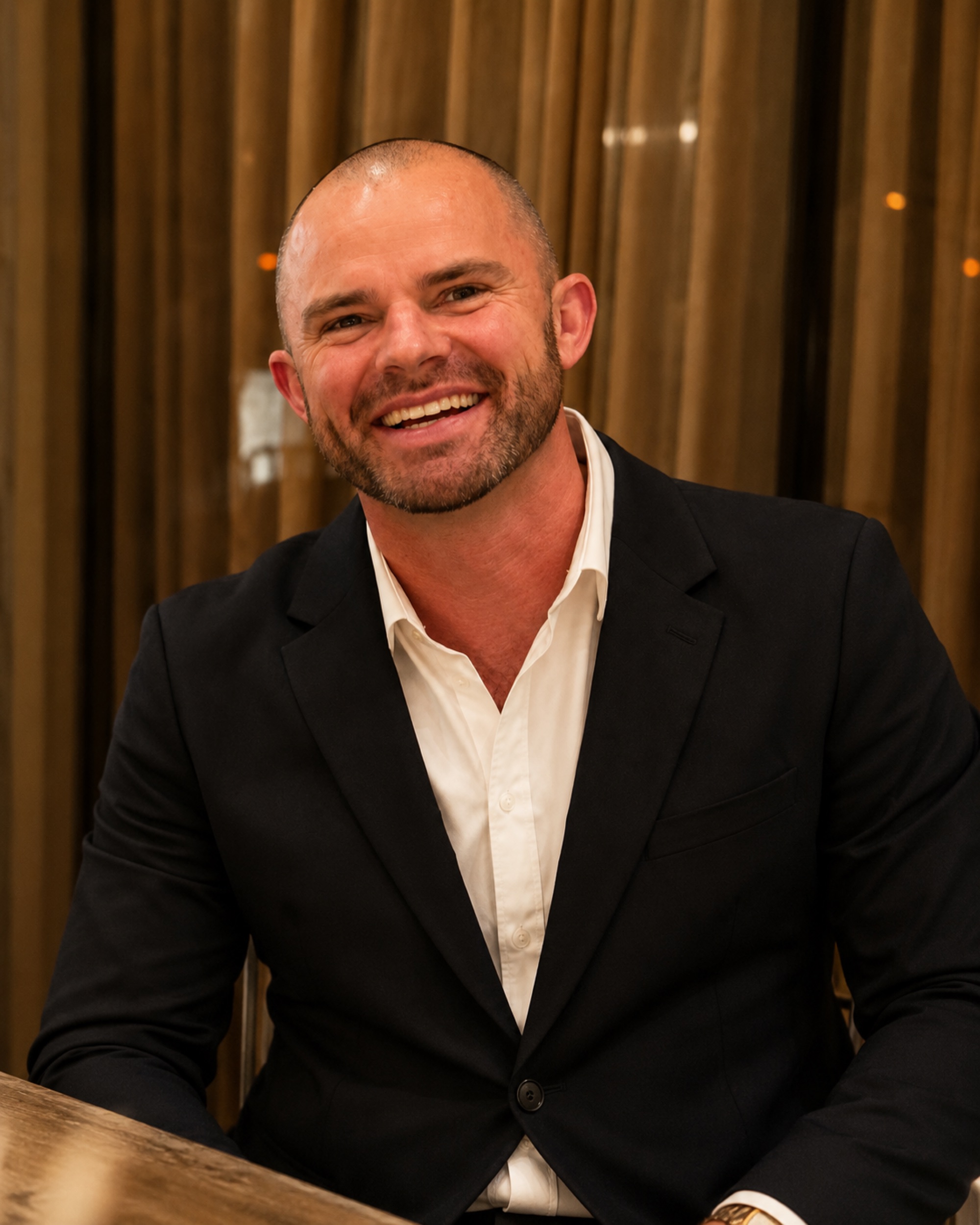 Jed Stokes, Co-Founder of JSD Collective, smiling in a dark jacket and white shirt