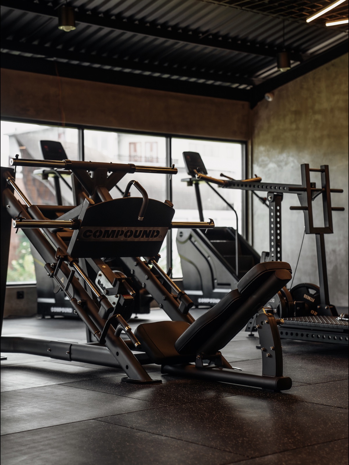 Compound-branded leg press and strength machines on the gym floor at The Compound Seminyak
