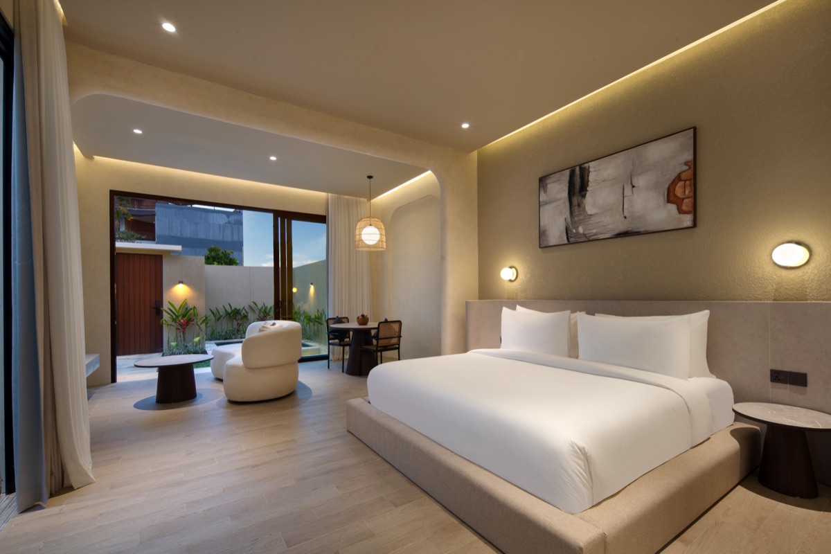 Lario Collection villa bedroom with a king bed, lounge chair and glass doors to a private garden